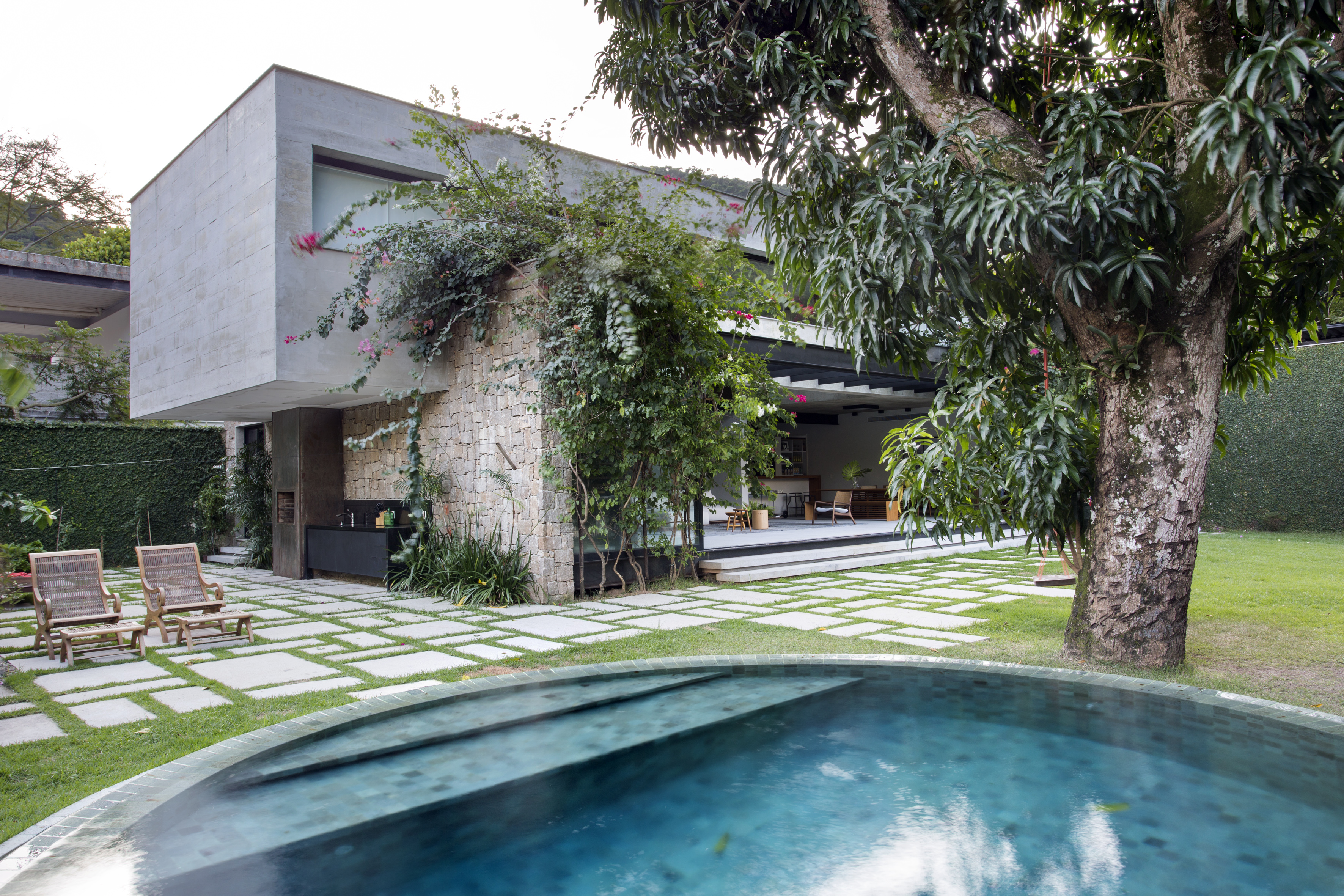 A varanda desta residência de 511 m² fica dentro de casa. Projeto Sabugosa Arquitetura. NA foto, sala integrada ao jardim, piscina e fachada.