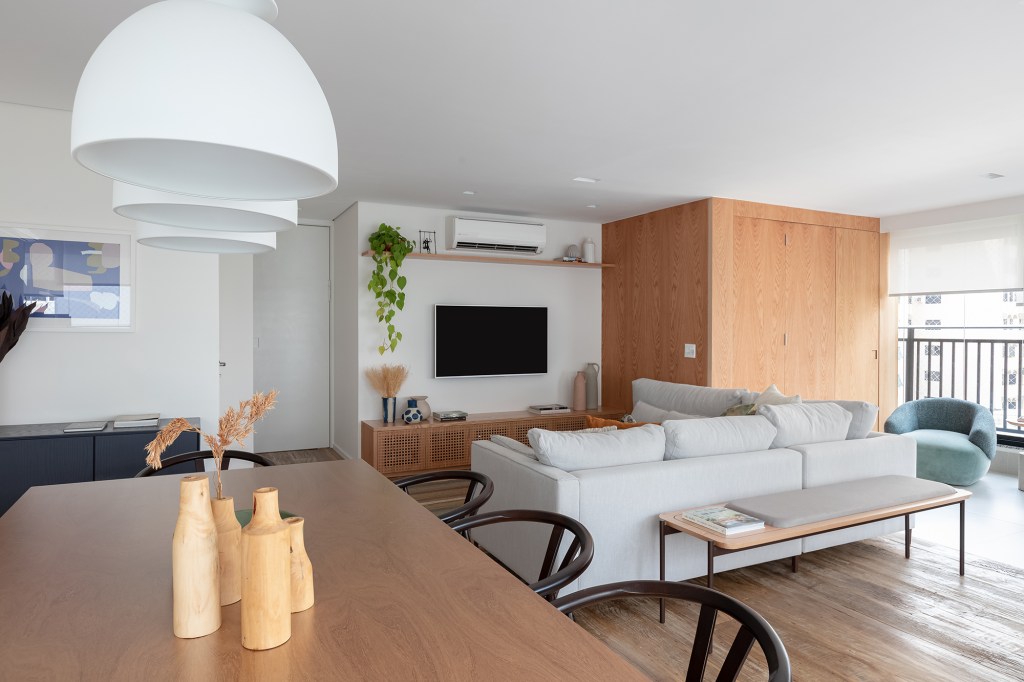 Apartamento de 147 m² ganha ambientes integrados e repletos de luz natural. Projeto de Estúdio Maré. Na foto, sala de estar, tv e jantar integradas à varanda.