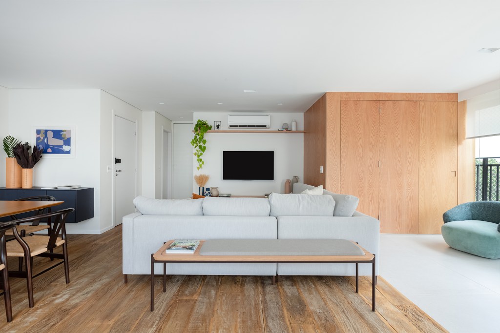 Apartamento de 147 m² ganha ambientes integrados e repletos de luz natural. Projeto de Estúdio Maré. Na foto, sala de TV com rack ripado e parede de madeira.