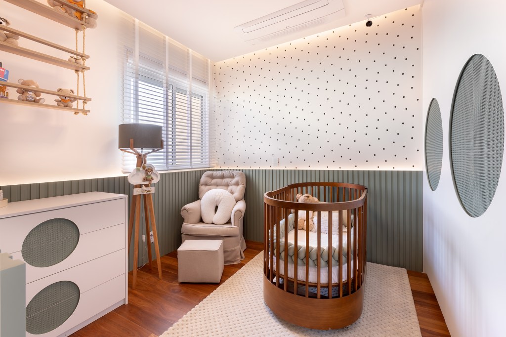 Apartamento de 200 m² é reformado para a chegada do novo bebê da família. Projeto de Priscila Comodaro. Na foto, quarto de bebê com lambri, tv e poltrona de amamentação.
