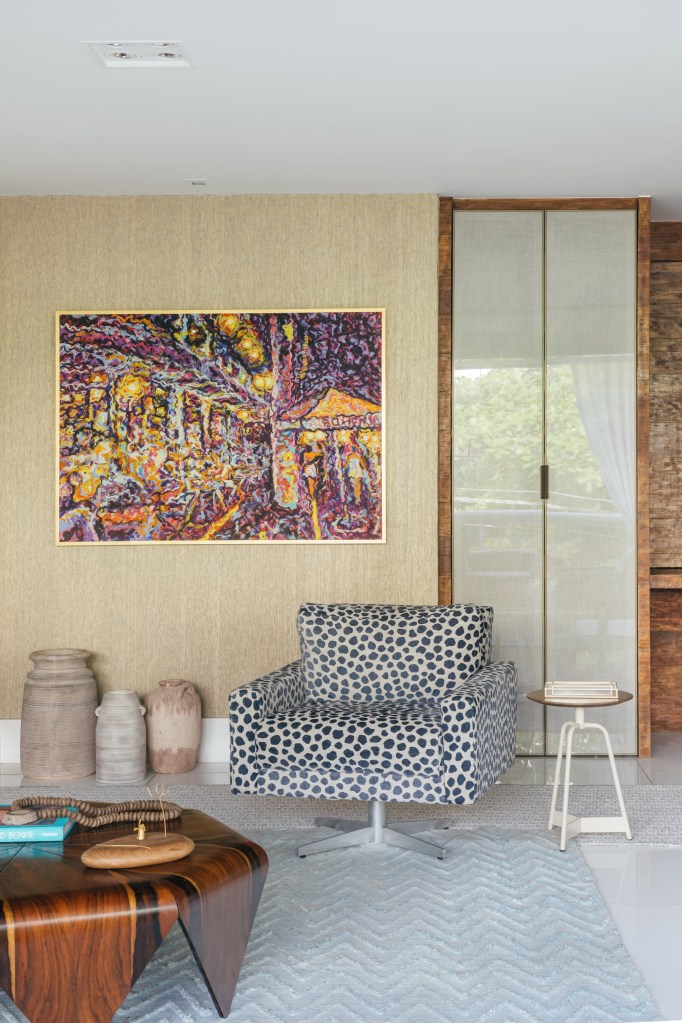 Apê de Ciro Bottini tem paleta Art Deco Navy com tons azuis e dourados. Projeto de Casa Cururu. Na foto, sala com poltrona de estampa animal e mesa de centro de madeira.