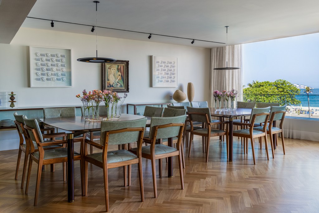 Apê de 300 m² tem vista para o mar e duas mesas iguais de jantar. Projeto de Andrea Chicharo. Na foto, sala de jantar com duas mesas e vista para o mar.
