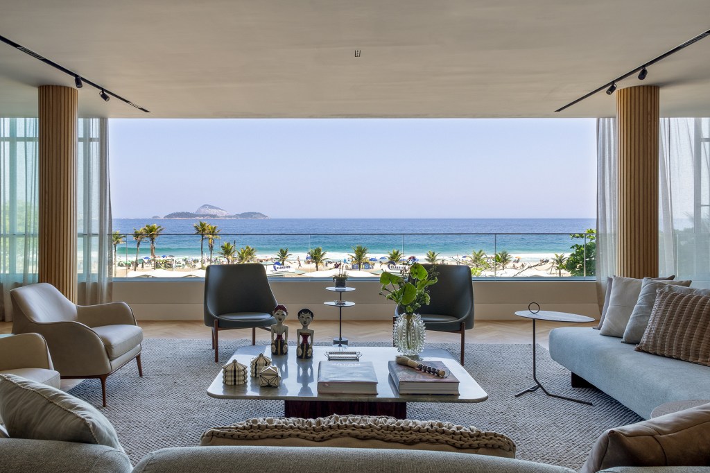 Apê de 300 m² tem vista para o mar e duas mesas iguais de jantar. Projeto de Andrea Chicharo. Na foto, sala de estar com vista para o mar.