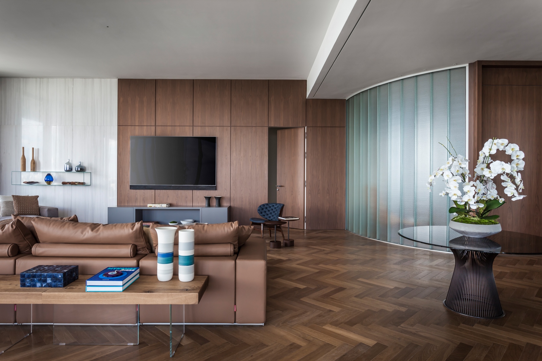 pê de 500 m² com vista para o mar de Miami tem mix de materiais no décor. Projeto de Andrea Chicharo. Na foto, sala com parede de madeira, parede curva e tv.
