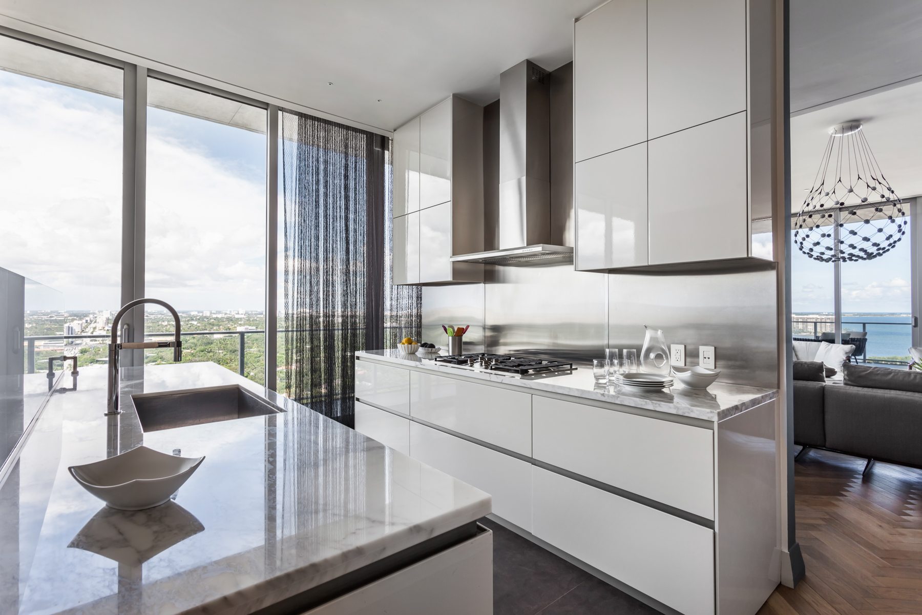 Apê de 500 m² com vista para o mar de Miami tem mix de materiais no décor. Projeto de Andrea Chicharo. Na foto, cozinha e sala de jantar com vista para o mar.