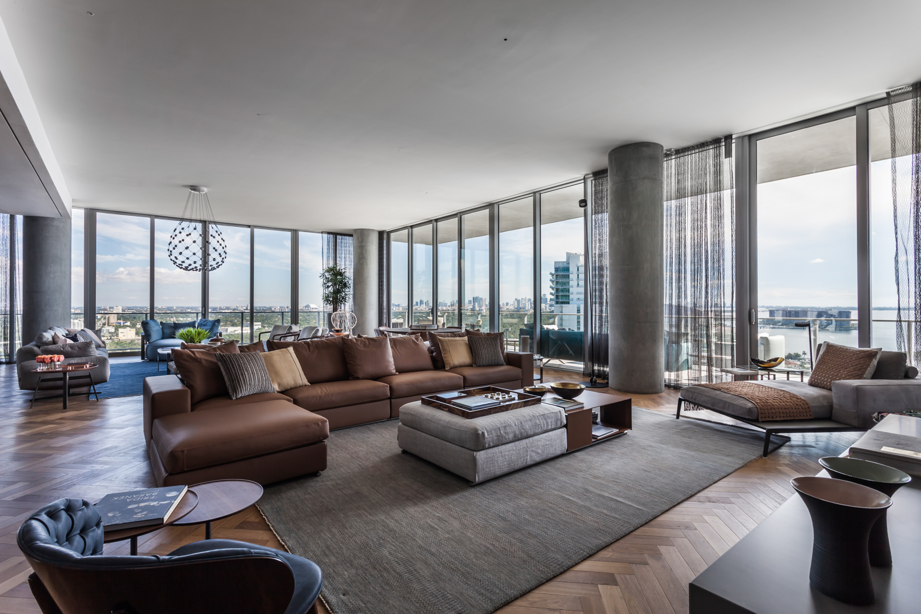 Apê de 500 m² com vista para o mar de Miami tem mix de materiais no décor. Projeto de Andrea Chicharo. Na foto, sala com vista para o mar, paredes de vidro e sofás.