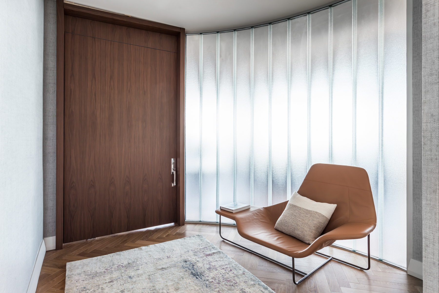 Apê de 500 m² com vista para o mar de Miami tem mix de materiais no décor. Projeto de Andrea Chicharo. Na foto, hall com cadeira e parede curva.