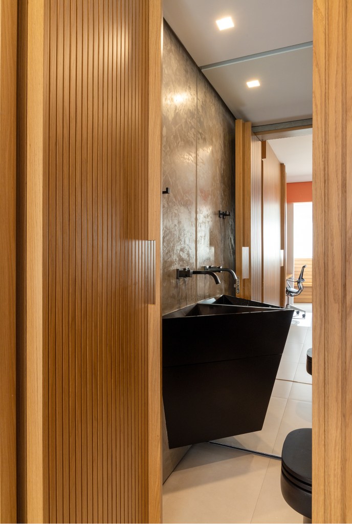 Apê de 90 m² tem cozinha com marcenaria preta e cuba triangular no lavabo. Projeto de Joaquim Meyer. Na foto, lavabo com pia triangular.