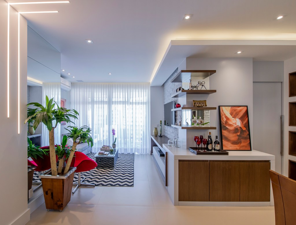 Apê de 90 m² ganha layout funcional após troca de paredes de lugar. Projeto de Campos & Olivetti Arquitetura. Na foto, sala de estar e jantar com marcenaria planejada e tapete chevron.