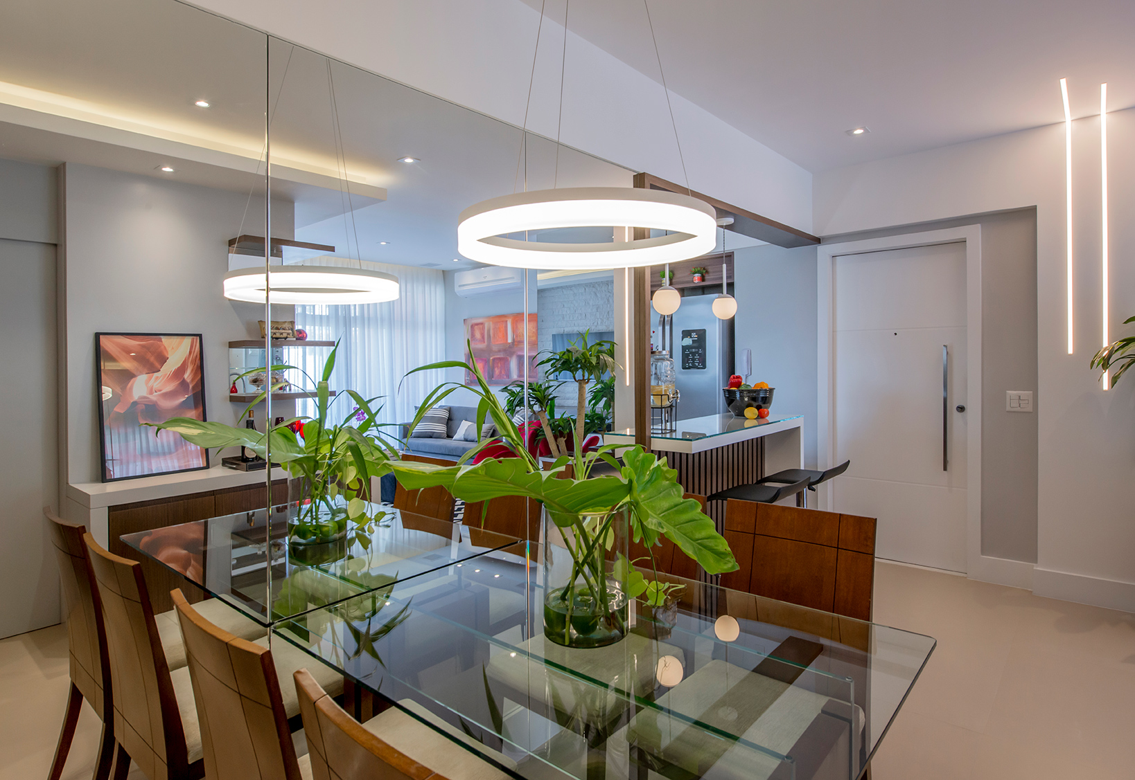 Apê de 90 m² ganha layout funcional após troca de paredes de lugar. Projeto de Campos & Olivetti Arquitetura. Na foto, sala de jantar com parede de espelho e cozinha integrada.