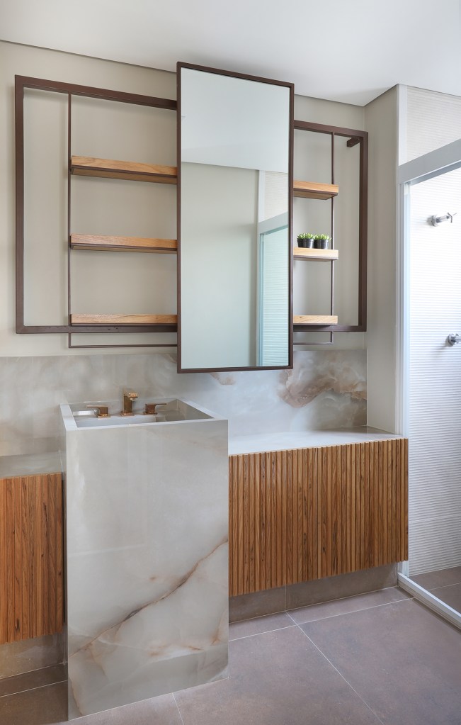 Apê descolado de 120 m² tem décor inspirado nos quadros do cliente. Projeto Inovando Arquitetura. Na foto, banheiro com gabinete ripado e pia esculpida.