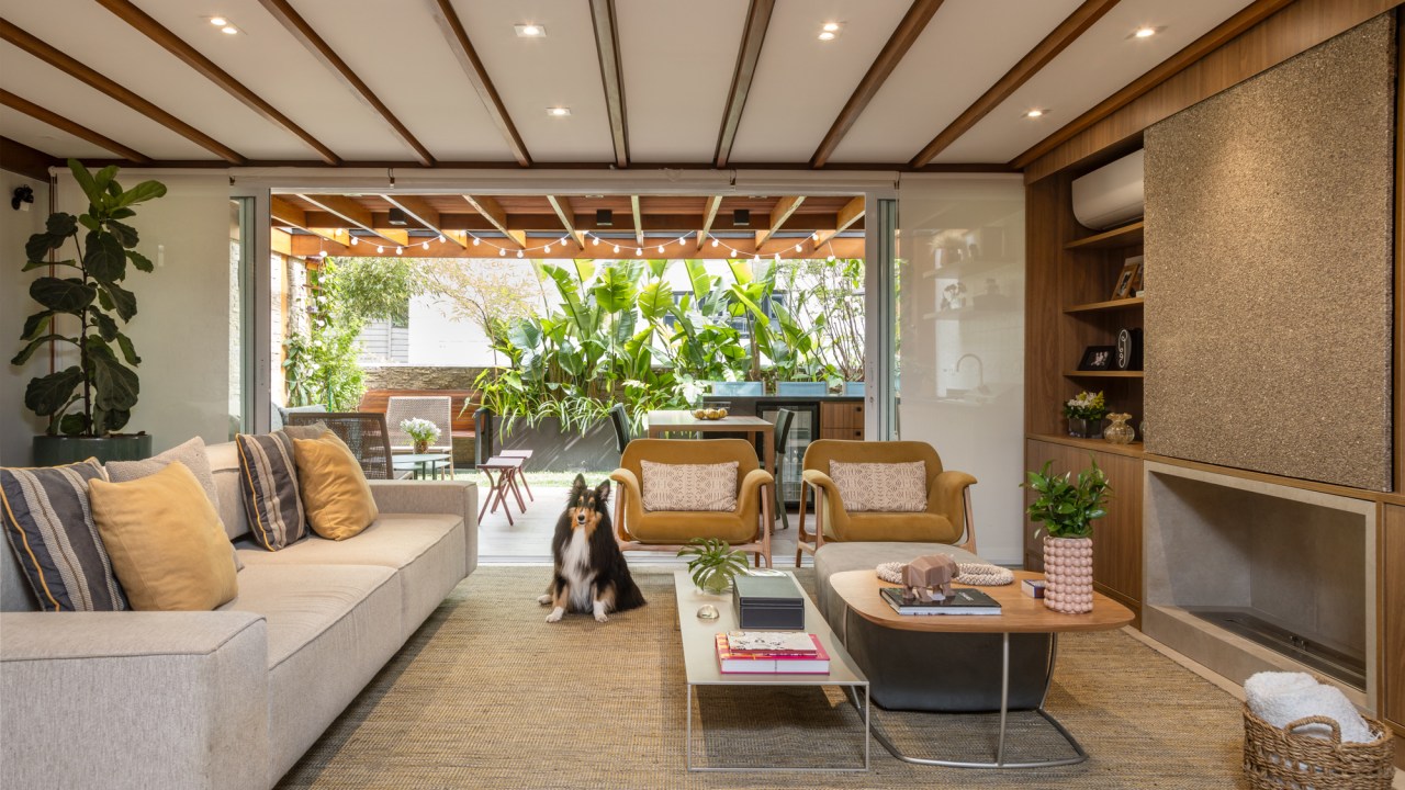 Apê garden tem academia compacta e varanda com gramado e muitas plantas. STAL Arquitetura. Na foto, sala integrada com varanda, tapete bege, sofá branco.