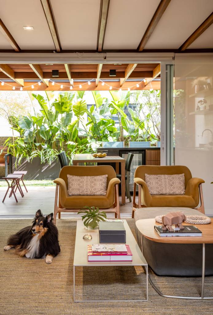 Apê garden tem academia compacta e varanda com gramado e muitas plantas. STAL Arquitetura. Na foto, sala integrada com varanda, tapete bege, sofá branco.