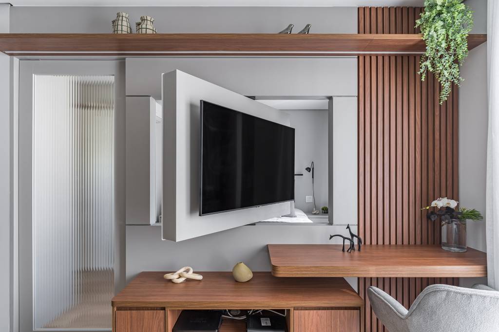 Apê de 42 m² ganha décor minimalista e cabeceira feita de varão de cortina. Projeto Inovando Arquitetura. Na foto, home office na sala com Tv giratória.