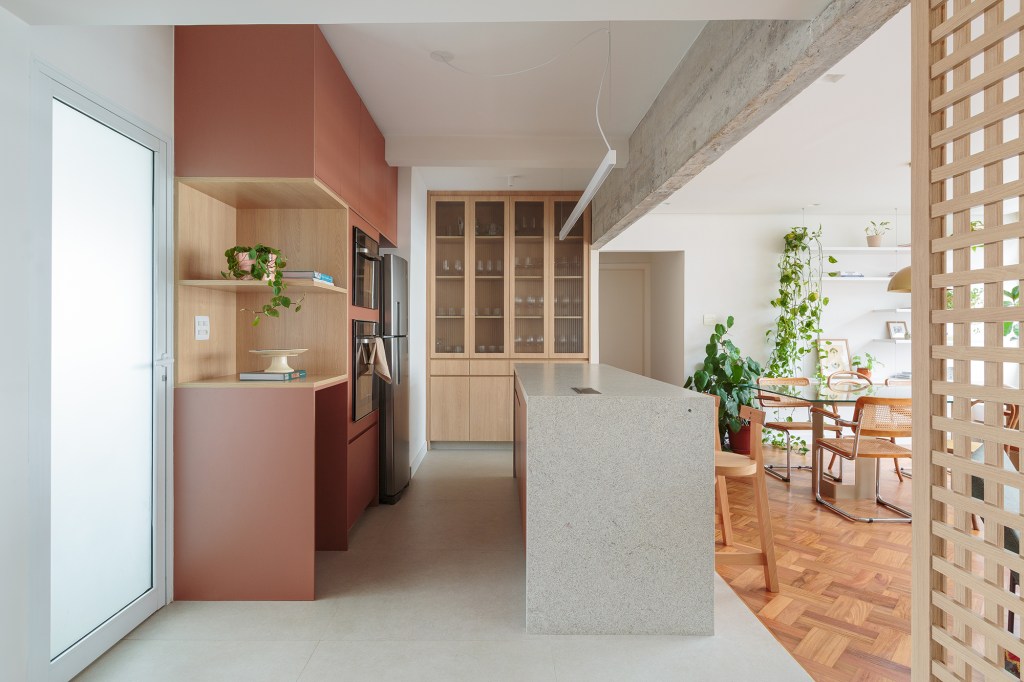 Banco com azulejos estampados e espaço pet são destaques no apê de 160 m². Projeto Estúdio Maré, Na foto, cozinha com ilha e marcenaria rosa. Parede de muxarabi.