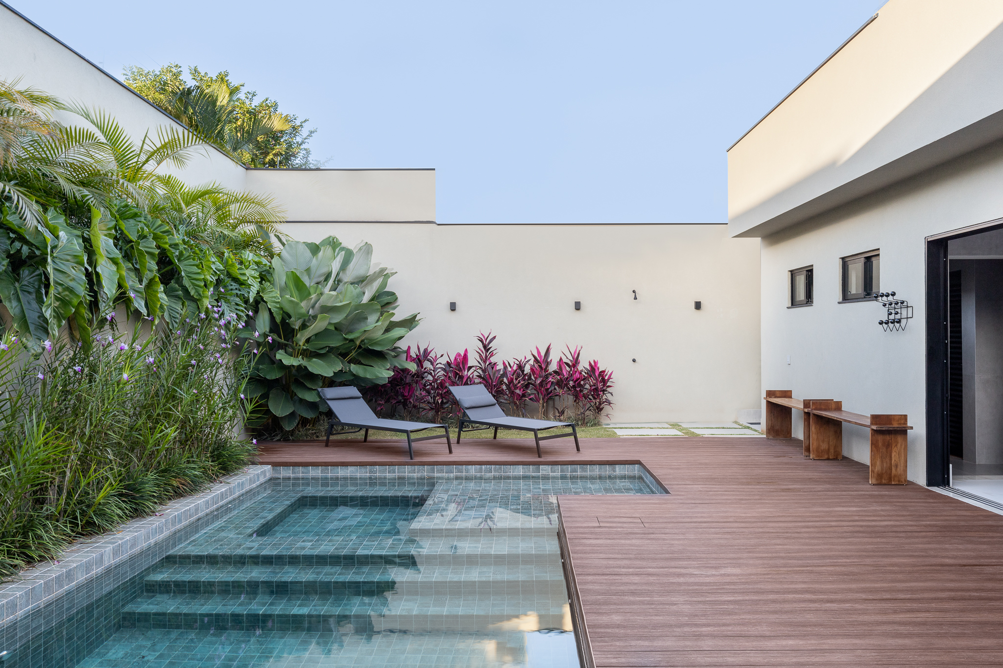 Casa com arquitetura clean foi pensada para as festas da família. Projeto de Visivo Arquitetura. Na foto, piscina com deque de madeira e plantas.