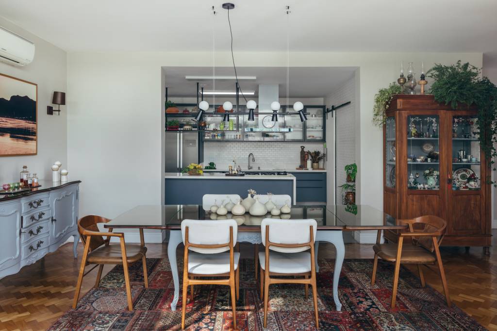 Casa de casal de 70 anos apaixonado por samba inspira-se na brasilidade. Projeto de Ana Cano. Na foto, sala de jantar vintage integrada com cozinha com marcenaria azul. Piso de taco.
