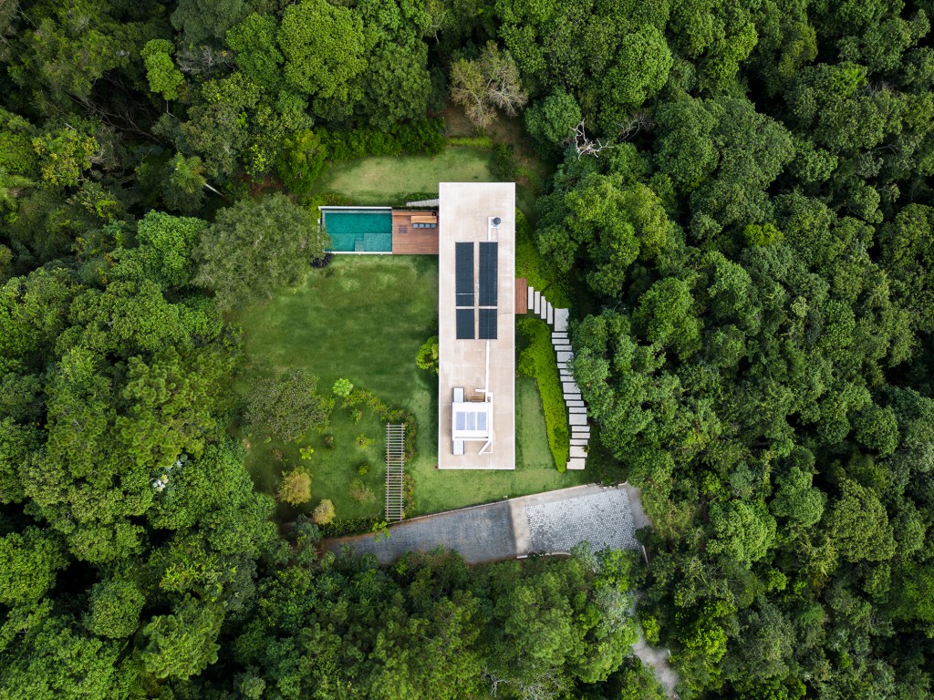 Casa de campo imersa na natureza parece flutuar em meio ao verde. Projeto de Conrado Ceravolo. Na foto, fachada da casa em meio ao jardim. Piscina e varanda. Vista aérea,