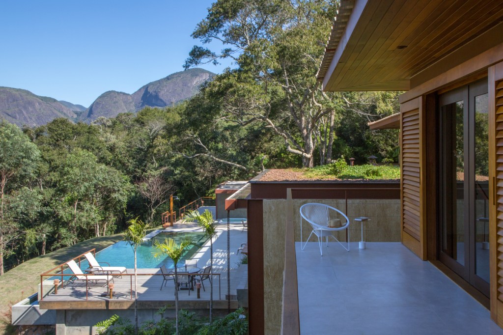 Casa na serra imersa na natureza possui vista espetacular para montanhas. Projeto de Andrea Chicharo. Na foto, varanda com vista para a serra e piscina.