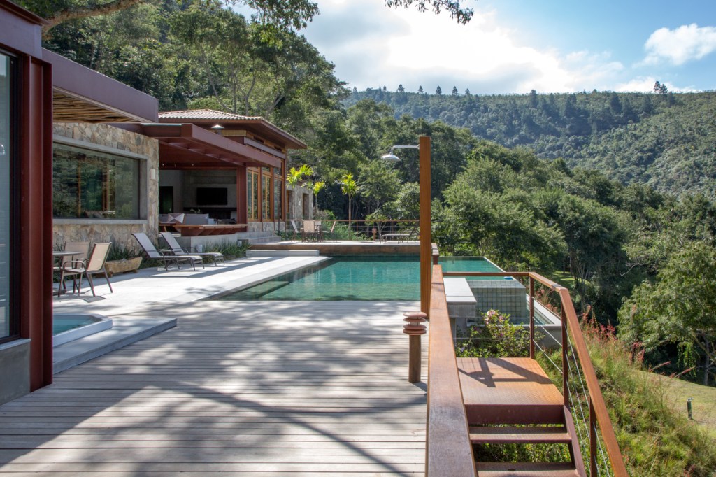 Casa na serra imersa na natureza possui vista espetacular para montanhas. Projeto de Andrea Chicharo. Na foto, varanda com piscina com vista para a serra.