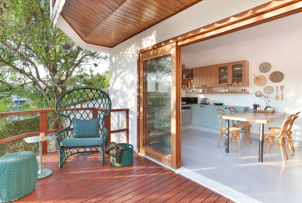 Cozinha de 15m² tem estilo contemporâneo com toque campestre. Projeto de Travessa Arquitetura. Na foto, varanda com deck de madeira e cadeira verde.