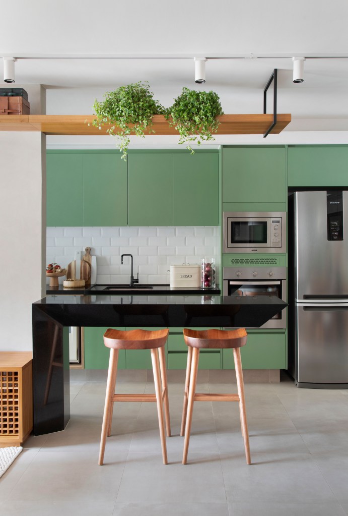 Cozinha com armário verde laqueado e bancada de granito é destaque em apê. Projeto de Ao Quadrado Arquitetura. Na foto, cozinha com marcenaria verde.