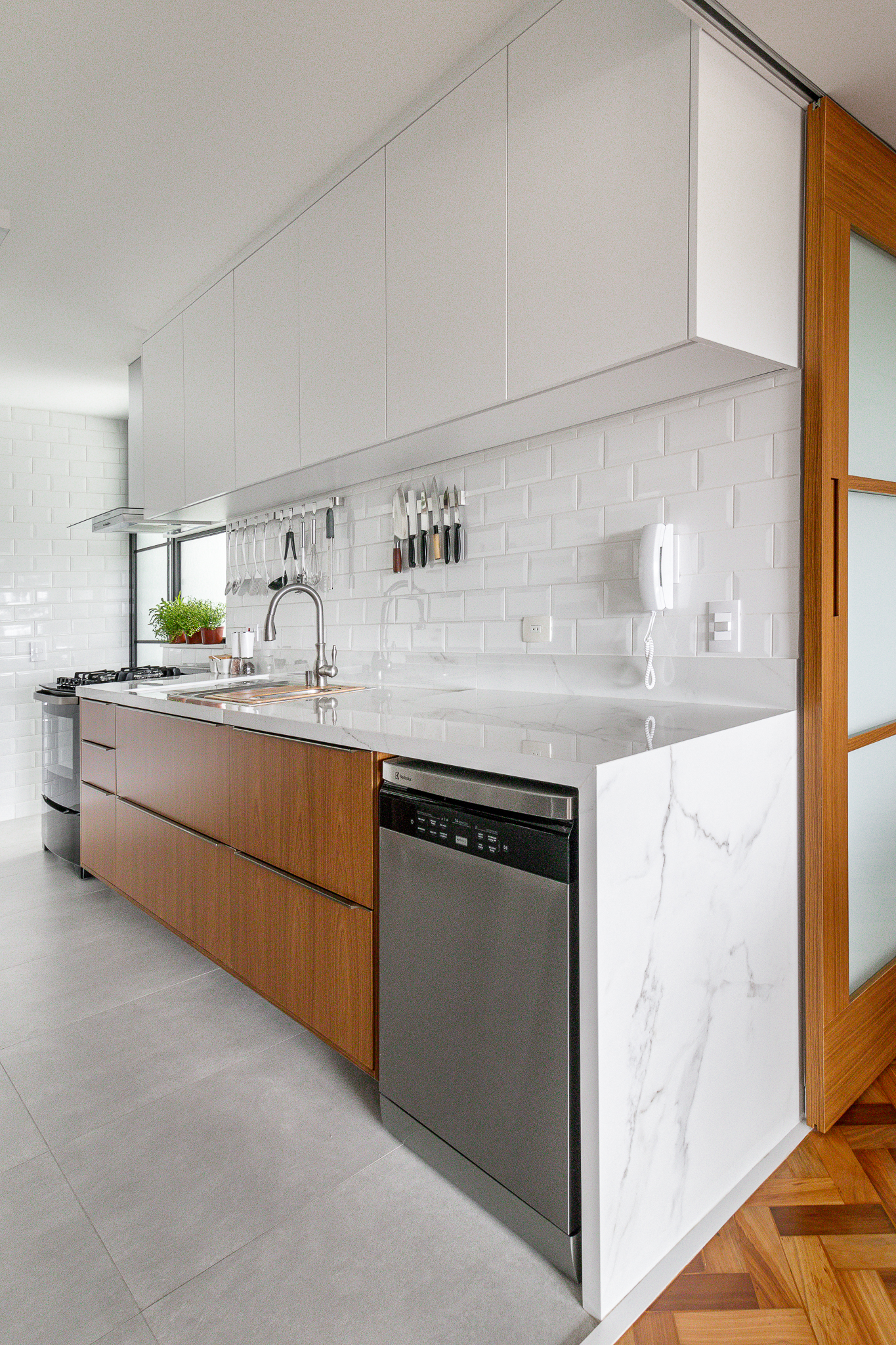 Cozinha minimalista foi pensada para abrigar muitos utensílios. Projeto de Inovando Arquitetura. Na foto, bancada de cozinha em lâmina marmorizada.