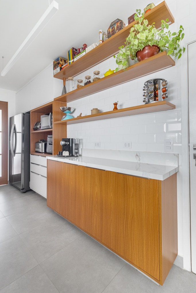 Cozinha minimalista foi pensada para abrigar muitos utensílios. Projeto de Inovando Arquitetura. Na foto, cozinha com prateleiras em marcenaria.