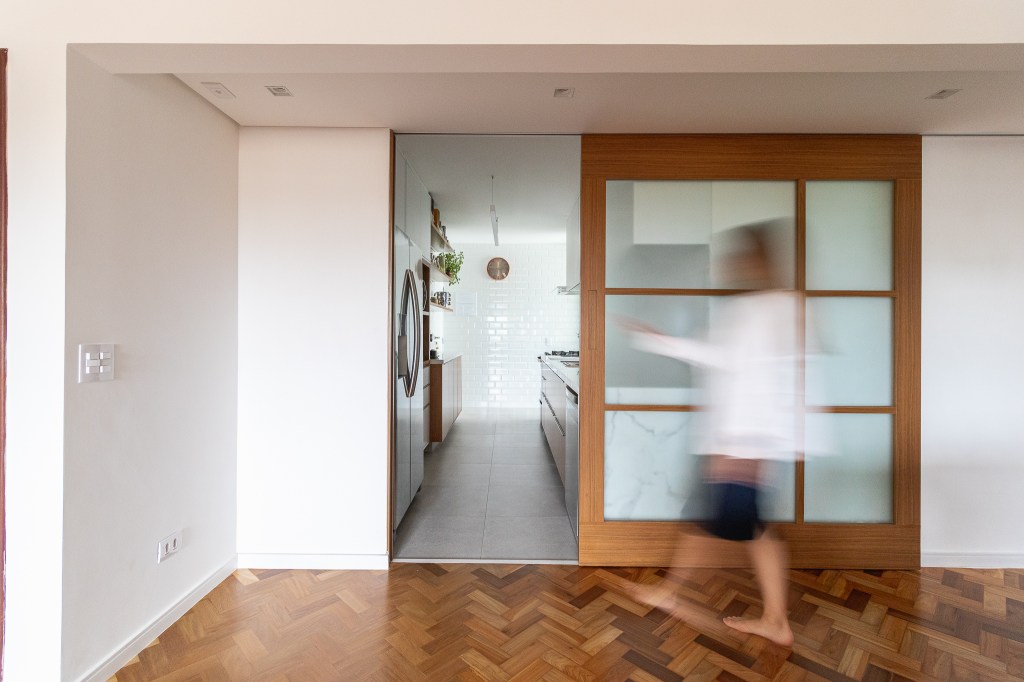 Cozinha minimalista foi pensada para abrigar muitos utensílios. Projeto de Inovando Arquitetura. Na foto, cozinha integrada com porta de correr.