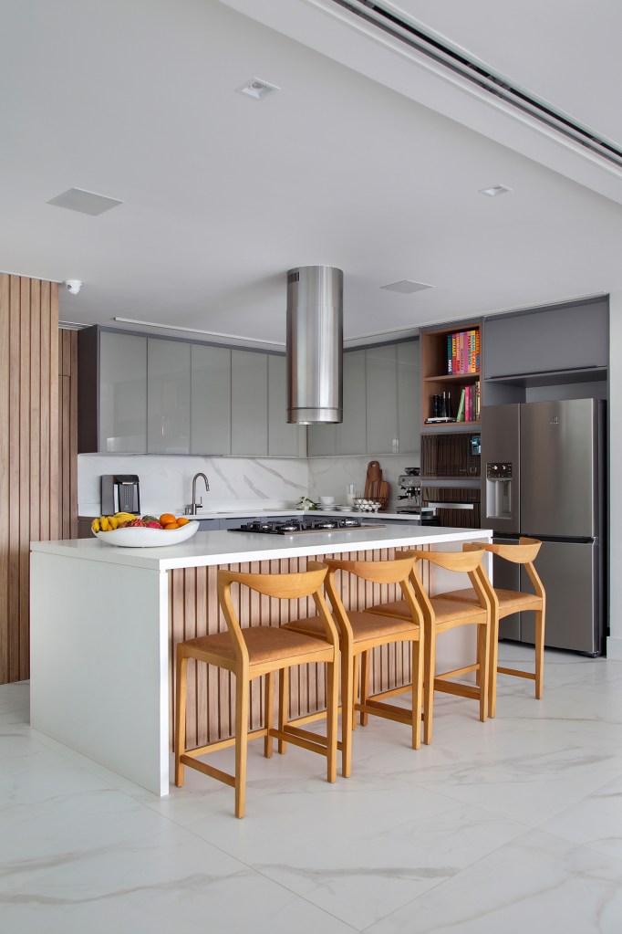 Duplex de 280 m² é minimalista, integrado e repleto de design brasileiro. Projeto de Tom Castro. Na foto, cozinha com ilha ripada e marcenaria cinza.