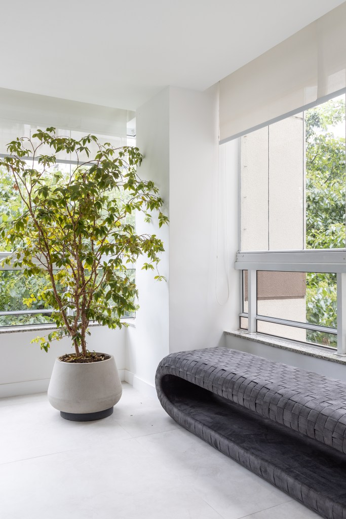 Janelas que trazem o verde para dentro e minimalismo definem apê de 170m². Projeto de AS Arquitetas. Na foto, varanda integrada com grandes janelas e árvore.
