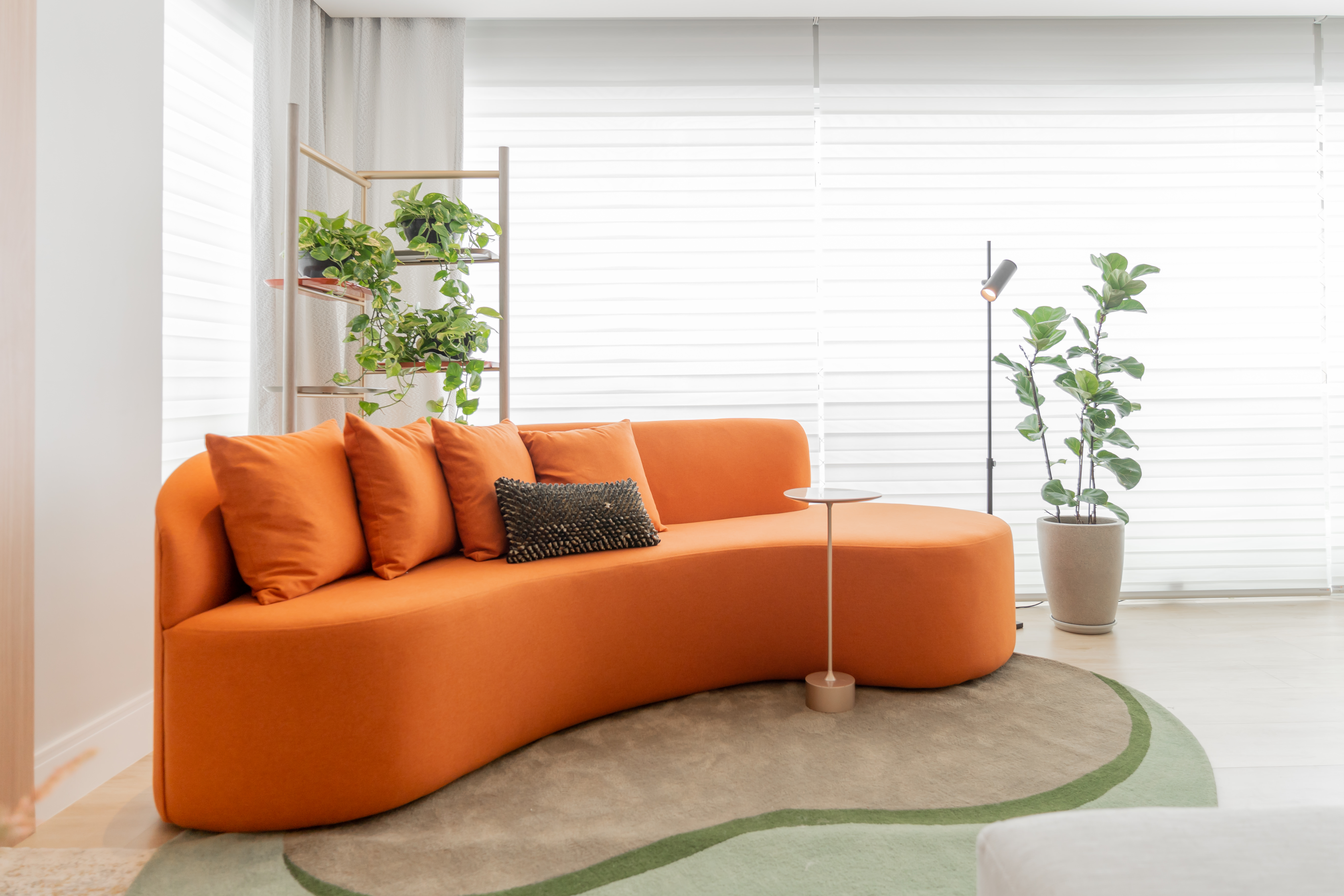 Móveis coloridos e mix de revestimentos dão o tom do décor neste apê. Projeto de Romário Rodrigues. Na foto, varanda com sofá curvo laranja e plantas.