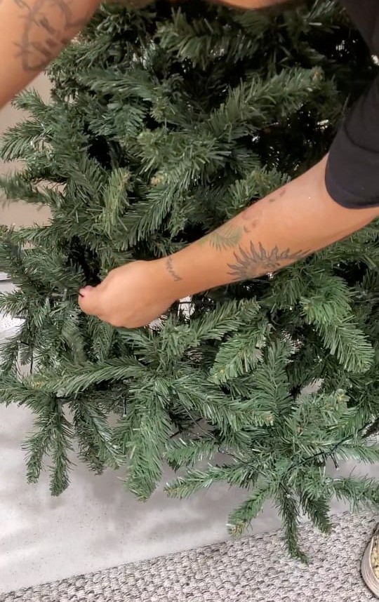 Passo a passo para montar uma Árvore de Natal igual às do shopping. Na foto, pisca-pisca sendo colocado na árvore de Natal.