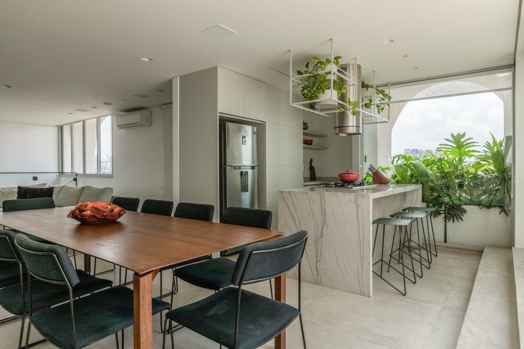 Reforma transforma apartamento de 362 m² em refúgio urbano minimalista. Projeto Inovando Arquitetura. Na foto, espaço gourmet com cozinha com ilha, prateleira suspensa e sala de jantar.
