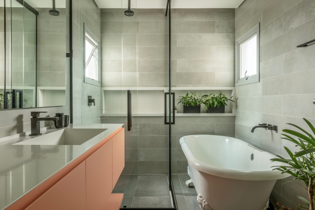 Reforma transforma apartamento de 362 m² em refúgio urbano minimalista. Projeto Inovando Arquitetura. Na foto, banheiro com banheira e marcenaria salmão.