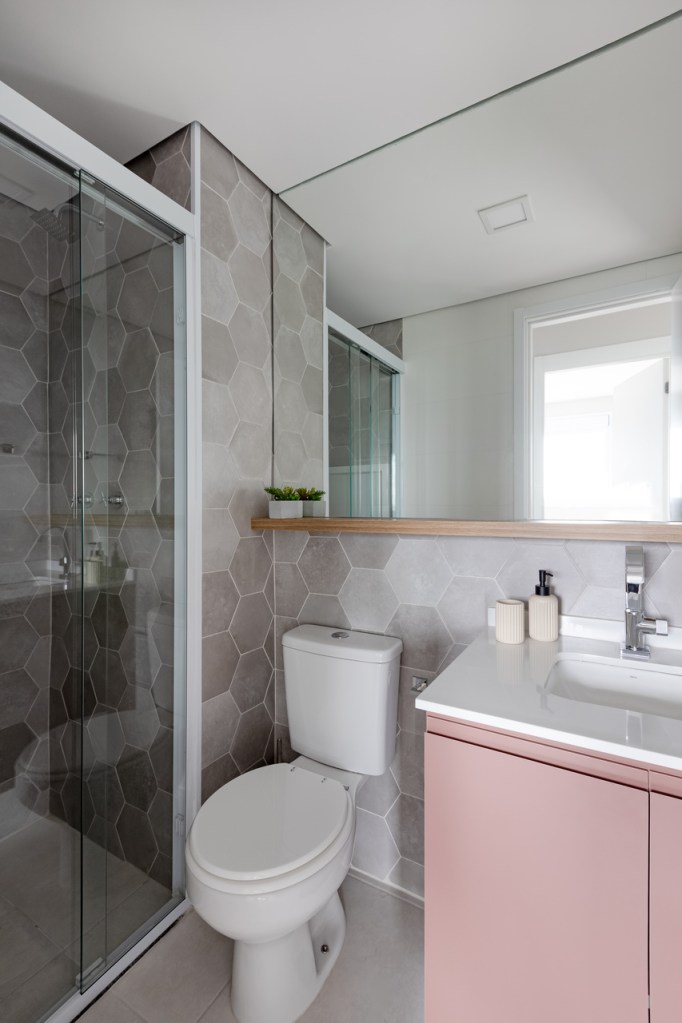 Sem quebra-quebra, apê de 53 m² ganha cores e canto alemão com sapateira. Projeto de Studio Monfré. Na foto, banheiro com revestimento hexagonal e marcenaria rosa.