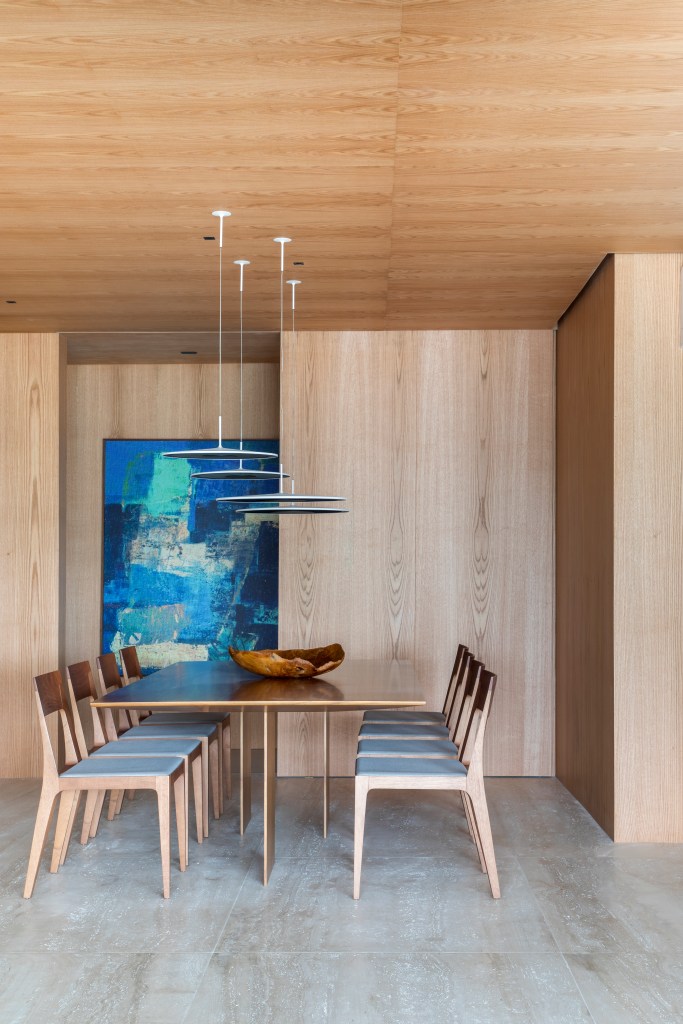 Varanda gourmet espaçosa com ilha travertino natural é destaque em apê. Projeto de Up3 Arquitetura. Na foto, sala de jantar com pórtico de madeira.