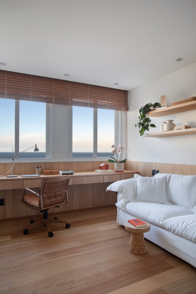 Com vista para o mar, apê de 302 m² foi pensado para o futuro da família. Projeto Sabugosa Arquitetura. Na foto, home office com vista para o mar e sofá branco.