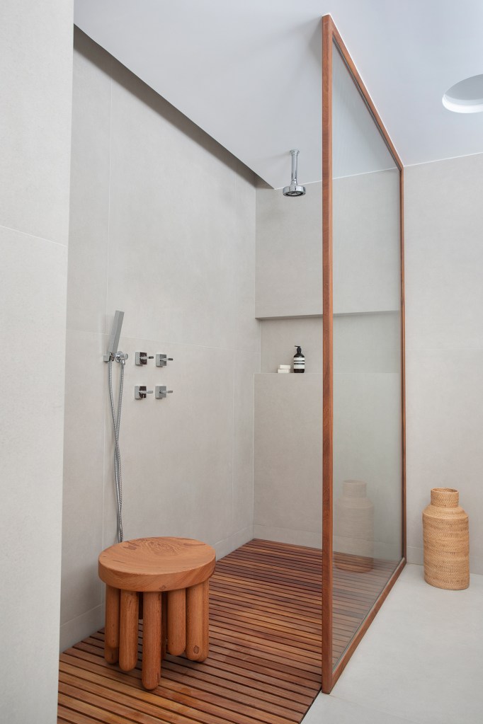 Com vista para o mar, apê de 302 m² foi pensado para o futuro da família. Projeto Sabugosa Arquitetura. Na foto, banheiro com deque de madeira e banco.
