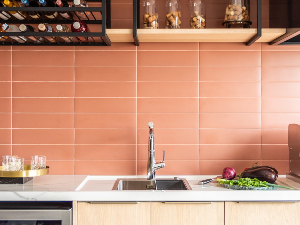 Ambientes Peach Fuzz. Projeto de BMA Studio. Na foto, cozinha com parede de azulejos na cor peach fuzz. Bancada branca.