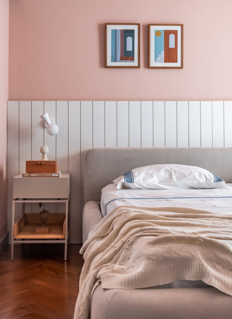 Ambientes Peach Fuzz. Projeto de Mari Milani. Na foto, quarto de casal com parede na cor peach fuzz e cabeceira branca de lambri.
