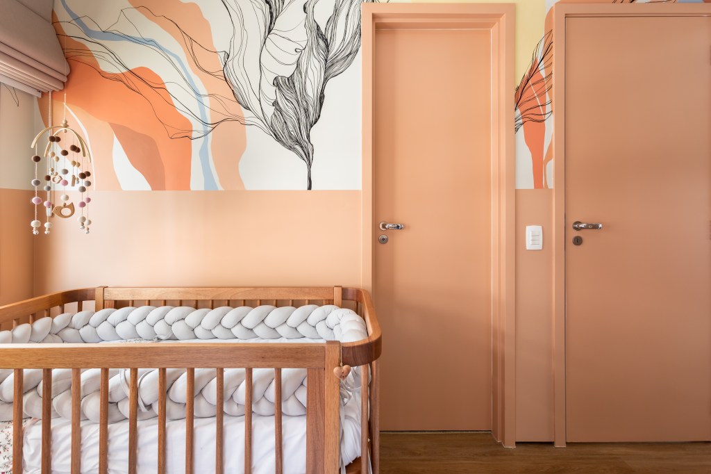 Ambientes Peach Fuzz. Projeto de Studio Tan Gram. Na foto, quarto infantil com paredes na cor peach fuzz e papel de parede botânico.