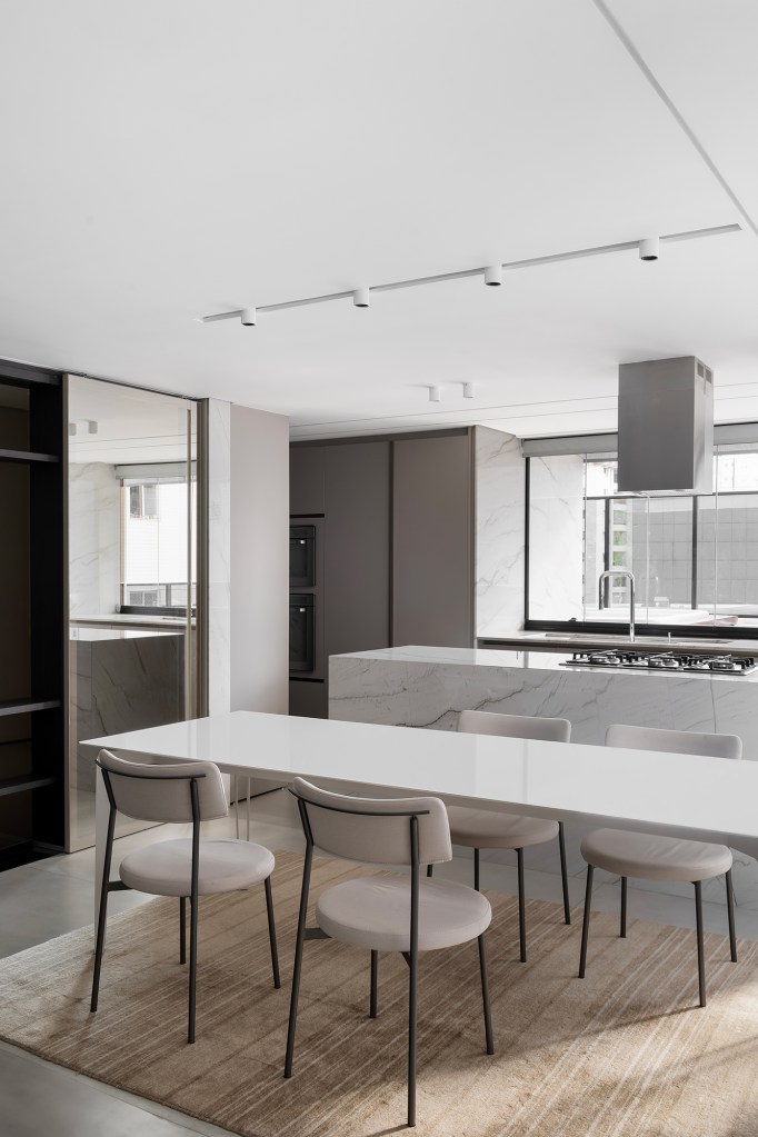 Apartamento de 160 m² em Belo Horizonte ganha décor minimalista e elegante. Projeto de Lucas Lage Arquitetura. Na foto, sala de jantar com cozinha integrada e ilha.