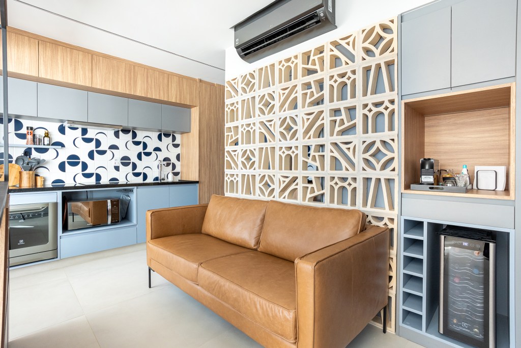 Apê de 36 m² tem lavanderia, home office e banheiro com chuveiro duplo. Projeto Loft 7 Arquitetura. Na foto, sala com parede de cobogós.