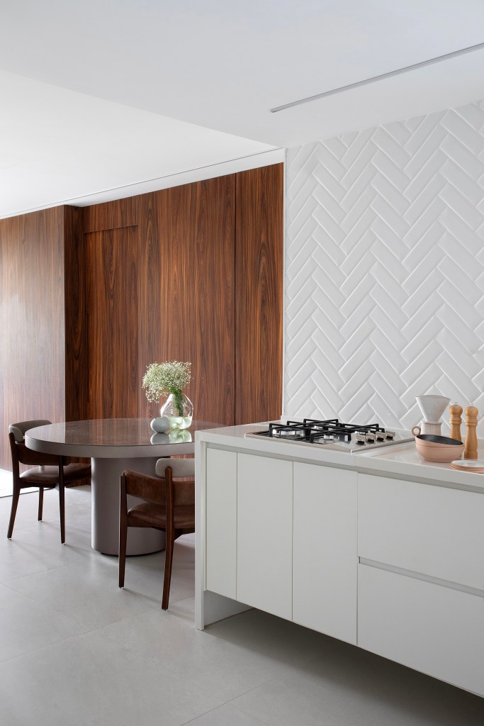 Apê de 75m² recebe décor minimalista em reforma de apenas 3 meses. Projeto de Roby Macedo. Na foto, sala de jantar com mesa redonda e cozinha minimalista.