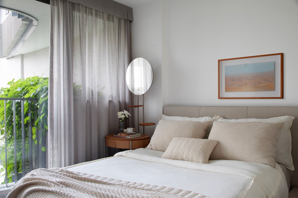 Apê de 75m² recebe décor minimalista em reforma de apenas 3 meses. Projeto de Roby Macedo. Na foto, quarto com cabeceira estofada e mesa lateral com espelho redondo.