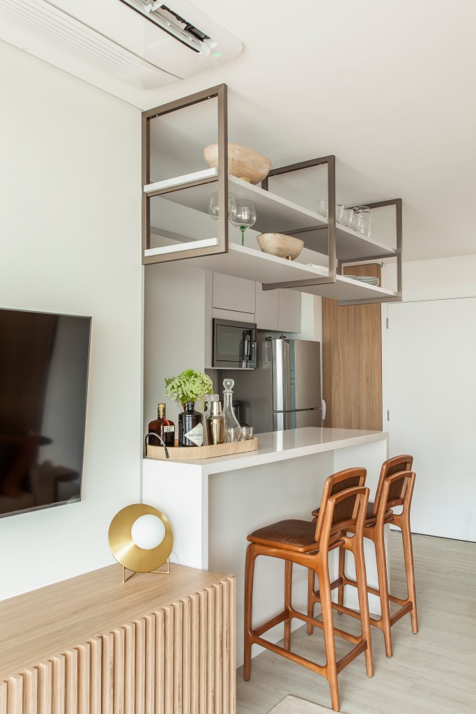 Apê compacto de 63m² usa móveis enxutos para aproveitar o espaço. Projeto de Carina Dal Fabbro. Na foto, cozinha integrada com bancada pequena de quartzo.