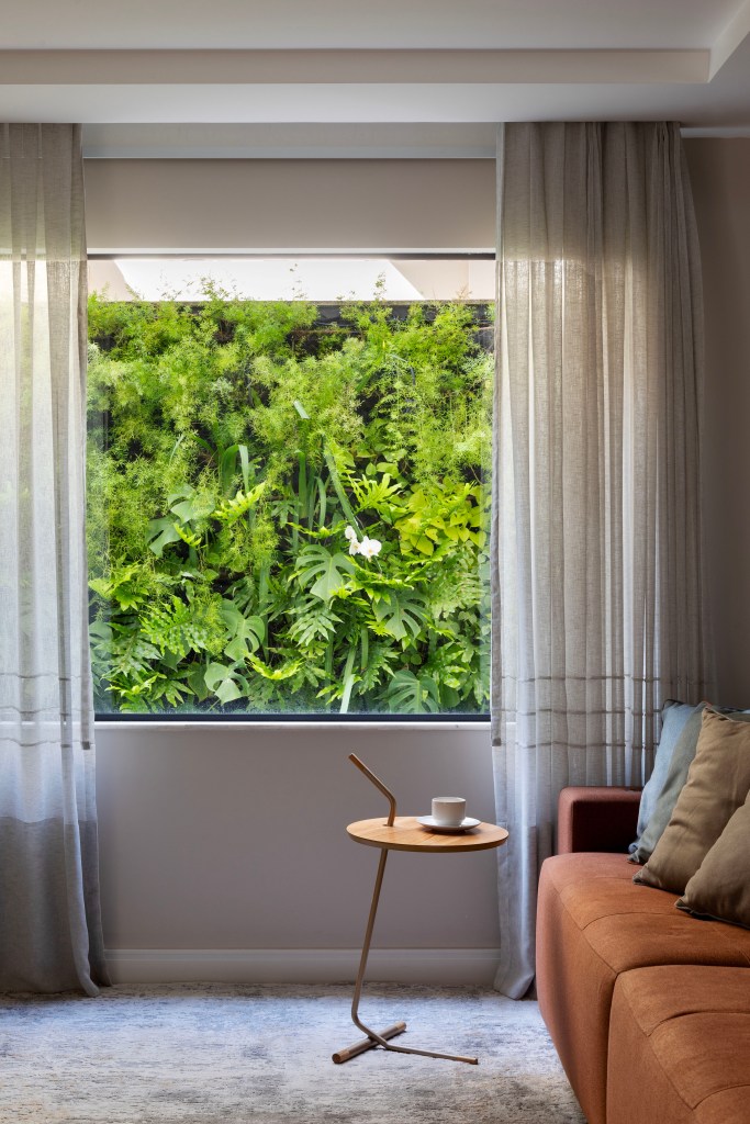 Área externa de 360m² ganha jardim que fica florido o ano todo. Paisagismo de Horto Girassol. Na foto, sala de estar com vista para jardim vertical.