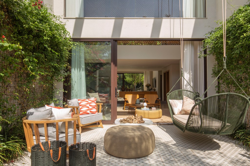 Casa de 350 m² tem quarto para quatro filhos e home theater na garagem. Projeto de Karen Pisacane. Na foto, varanda com jardim e poltrona suspensa.