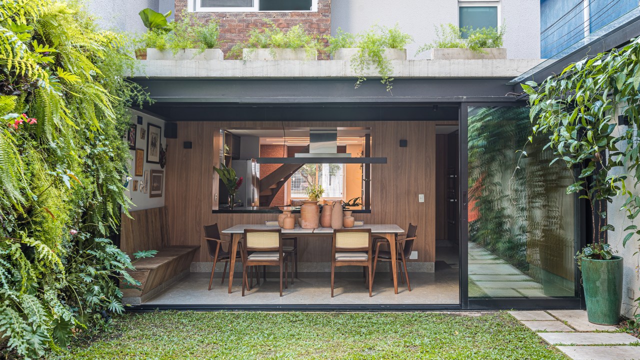 Casa de vila tem jardim com rede, cozinha integrada e muito charme. Projeto de Marcela Fazio Arquitetura. Na foto, área externa da casa com jardim e rede.